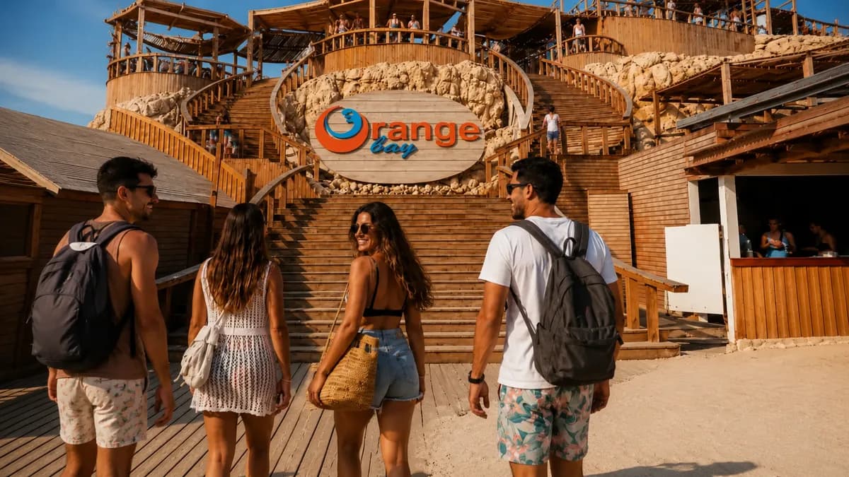 Four guests walking up the boardwalk to the wooden Orange Bay island entrance sign and staircase after arriving by speedboat from Hurghada