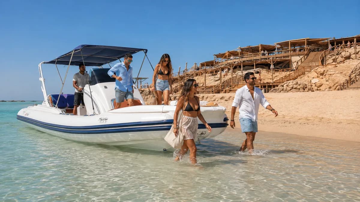 Guests stepping off a private speedboat straight onto the shallow white sandbank of Orange Bay island, with the wooden terraces and rocks behind